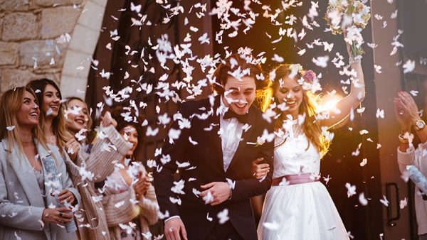 Newly married couple coming out of the church and guests throwing confetti at them.