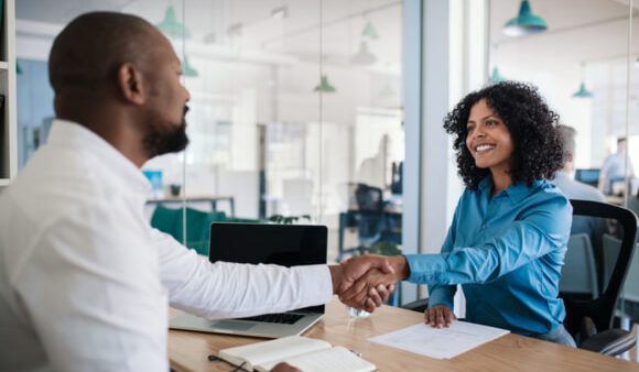 man and woman shaking hands over desk