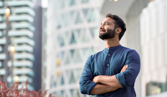 Confident rich eastern Indian business man executive standing in modern big city looking and dreaming of future business success, thinking of new goals, business vision and leadership concept.