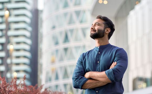 Confident rich eastern Indian business man executive standing in modern big city looking and dreaming of future business success, thinking of new goals, business vision and leadership concept.