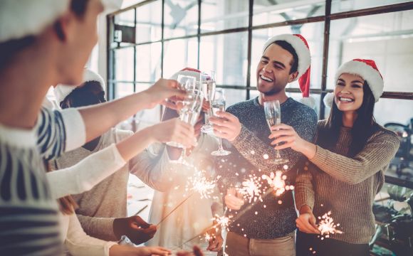 Multiracial young creative people are celebrating holiday in modern office. Group of young business people are drinking champagne in coworking.