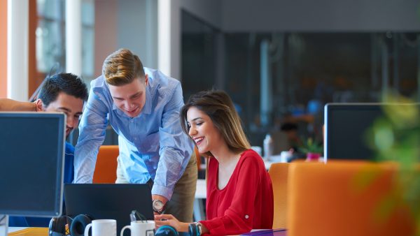 Group of three working at a desk with PC